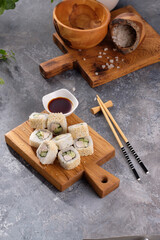Roll made of Fresh cucumber and chicken and salad inside in a gray background. Delicious food. Beautiful still life with a portion of rolls on a wooden board.