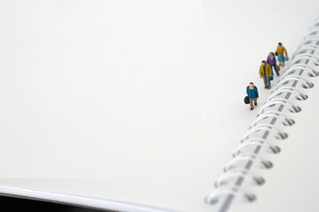 Miniature people in group walking on white blank Book. Business concept with copy space and white...