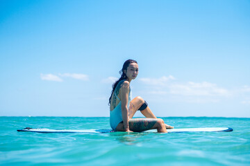 Portrait of surfer girl on surf board in blue ocean