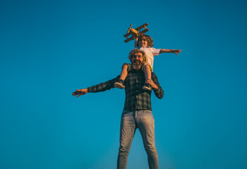 Obraz premium Father carrying his son on shoulders. Two generations of men father and son have fun and playing with toy airplane. Family relationship with son. Love daddy.