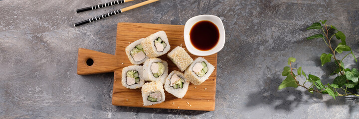 Roll made of Fresh cucumber and chicken and salad inside in a gray background. Delicious food. Beautiful still life with a portion of rolls on a wooden board.