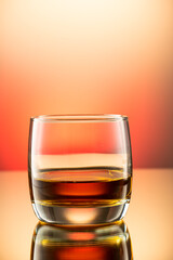 whiskey with ice splash in a glass on a colored gradient background