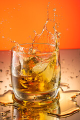 whiskey with ice splash in a glass on a colored gradient background