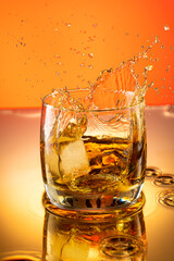 whiskey with ice splash in a glass on a colored gradient background