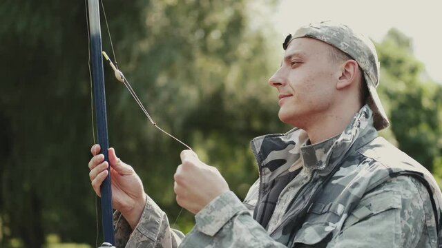 Closeup of fisher holding a spinning and pulling on the thread. The man is fishing at the pond in a park. Fishing hobby.