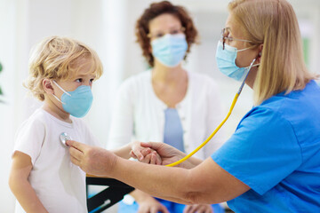 Doctor examining sick child in face mask