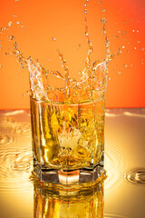 whiskey with ice splash in a glass on a colored gradient background