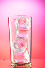 pieces of pure real ice in a glass on a colored gradient background, cubes are rounded