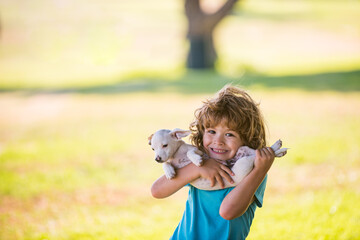 Cute child boy feels delighted, carries little puppy dog, expresses tender emotions, care and love to small doggy. Tenderness friends hugs. © Volodymyr