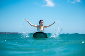 Portrait of surfer girl on surf board in blue ocean