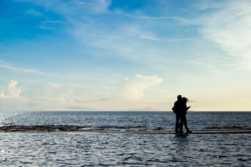 Fototapeta premium Silhouettes of people on a coast of a sea.