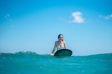 Fototapeta premium Portrait of surfer girl on surf board in blue ocean