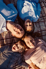 Happy family have a rest together in a picnic outdoors. Blue pink clothes, casual. Beautiful mother, father and children, top view.