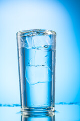 pieces of pure real ice in a glass on a colored gradient background, cubes are rounded