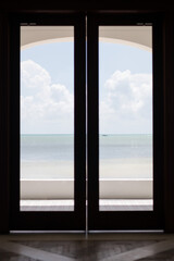 Calm beach ocean water texture sand captured and framed by a large grand timber door frame entry way picture holiday travel tourist