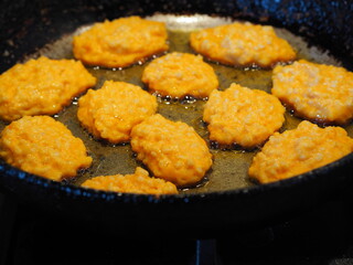 Diet pancakes made from natural pumpkin and millet are fried in a black pan. Home cooking, rustic style