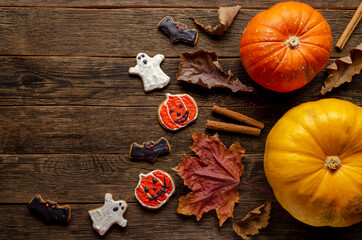 gingerbread for Halloween and fresh pumpkin on wooden background.