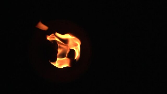 The fire burns on a torch wick on a black background, fire show. Slow motion