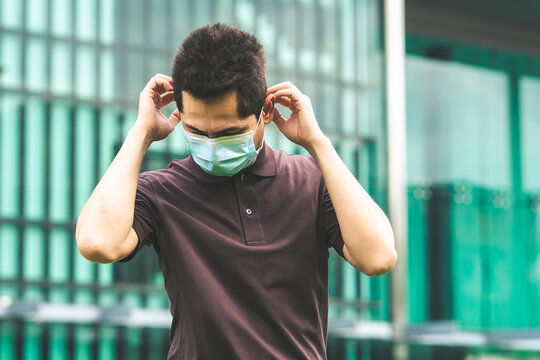 Handsome young man standing outdoors wearing medical mask to protect others from virus spread