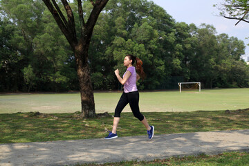 beautiful young south east Asian Chinese woman jogging running outdoor green tree park