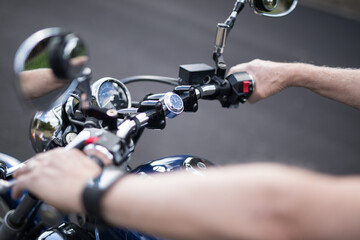 Fototapeta na wymiar View of a male active senior man riding his bike looking down at the handlebars of his motorbike cycle chrome guages mirros hand instrumentation outdoors on a bright day
