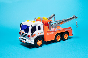 Toy orange tow truck on blue background. Children's car for loading and transporting cars. Copyspace.