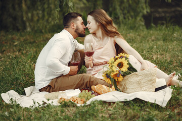 Couple in a field. Brunette in a white dress. Pair sitting on a grass.