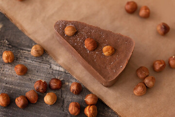 Chocolate cheesecake on a wooden Board with scattered hazelnuts