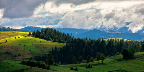 beautiful scenery of mountainous countryside. clouds above the hills rolling in to the distant valley. carpathian landscape in dappled light. dramatic weather conditions.