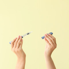 Female hands with syringe for insulin injection on color background. Diabetes concept