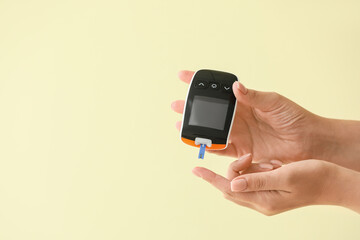 Fototapeta na wymiar Female hands with glucometer on color background. Diabetes concept