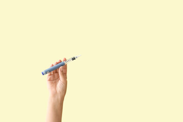 Female hand with syringe for insulin injection on color background. Diabetes concept