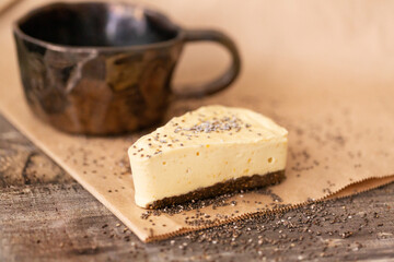 Cheesecake on craft paper with scattered sesame seeds and a cup of coffee