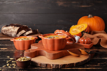 Tasty pumpkin cream soup in pots on table