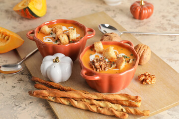 Tasty pumpkin cream soup in pots on table