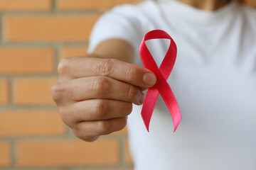 Woman with pink awareness ribbon against brick wall background