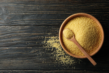 Bowl with couscous and spoon on wooden background