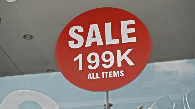 Red round sign hanging on a glass window with the inscription Sale 199 K all items