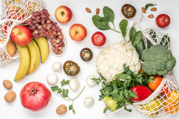 Healthy vegan food in cotton reusable net mesh bag on white wooden table. Shopping food supermarket and clean vegan eating concept