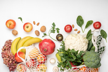 Healthy vegan food in cotton reusable net mesh bag on white wooden table. Shopping food supermarket and clean vegan eating concept