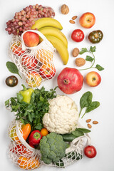 Healthy vegan food in cotton reusable net mesh bag on white wooden table. Shopping food supermarket and clean vegan eating concept