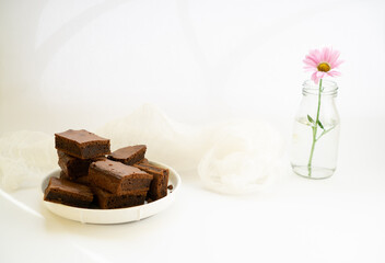 Chocolate brownie sliced into square slices on a white plate.