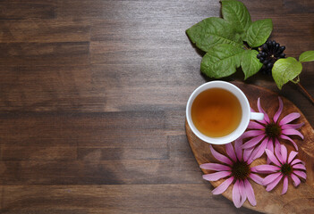 Echinacea and Eleutherococcus flowers on wooden background with tea