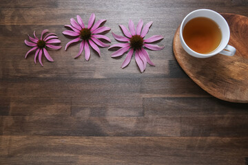 Obraz na płótnie Canvas echinacea flowers on wooden background with tea