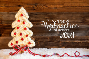 German Calligraphy Frohe Weihnachten Und Ein Glueckliches 2021 Means Merry Christmas And A Happy 2021. White Fabric Christmas Tree With Red Ball Ornament. Brown Rustic Wooden Background With Snow