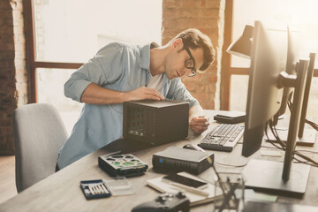 Portrait of his he nice attractive busy focused guy repairing part component pc cpu hard disk drive...