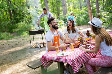 Group of happy friends eating and toasting at garden barbecue