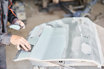 Repairing car body, Application putty close up. The mechanic repair the car. Work after the...