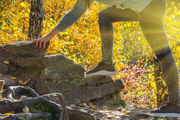 Female feet in sports sneakers on rocks. Hiking young woman goes in for sports, running in the mountains. Climbs mountains in sunlight. Backlight. Activity tourism