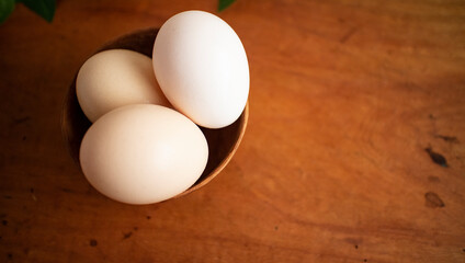 Three fresh white eggs in a wooden cup on a wooden table
木製テーブルの上にある木のカップに入った３つの白い卵 2
